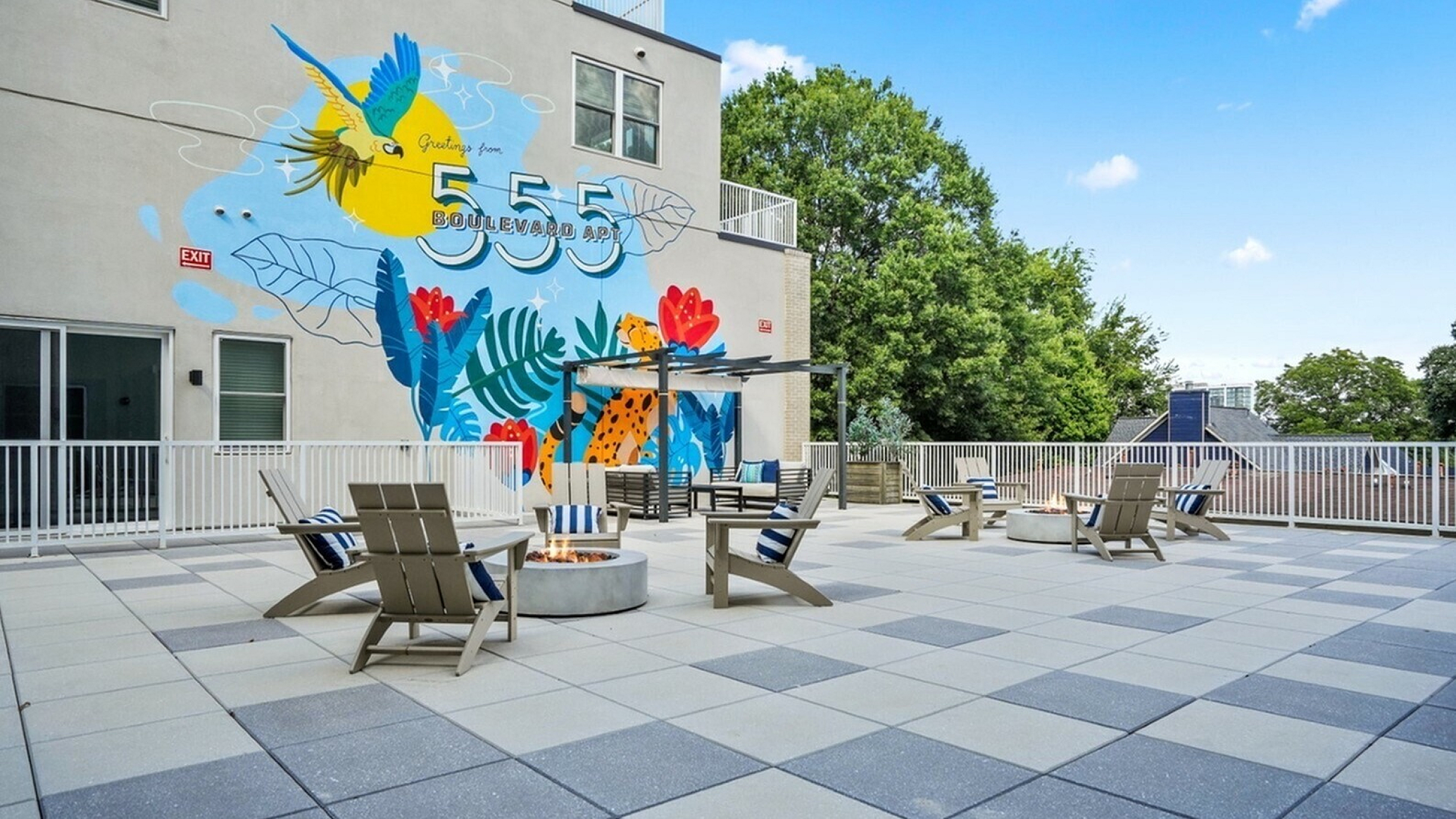 Vibrant outdoor terrace at 555 Boulevard Apartments featuring colorful mural, cozy fire pits, and stylish seating for a perfect urban retreat.