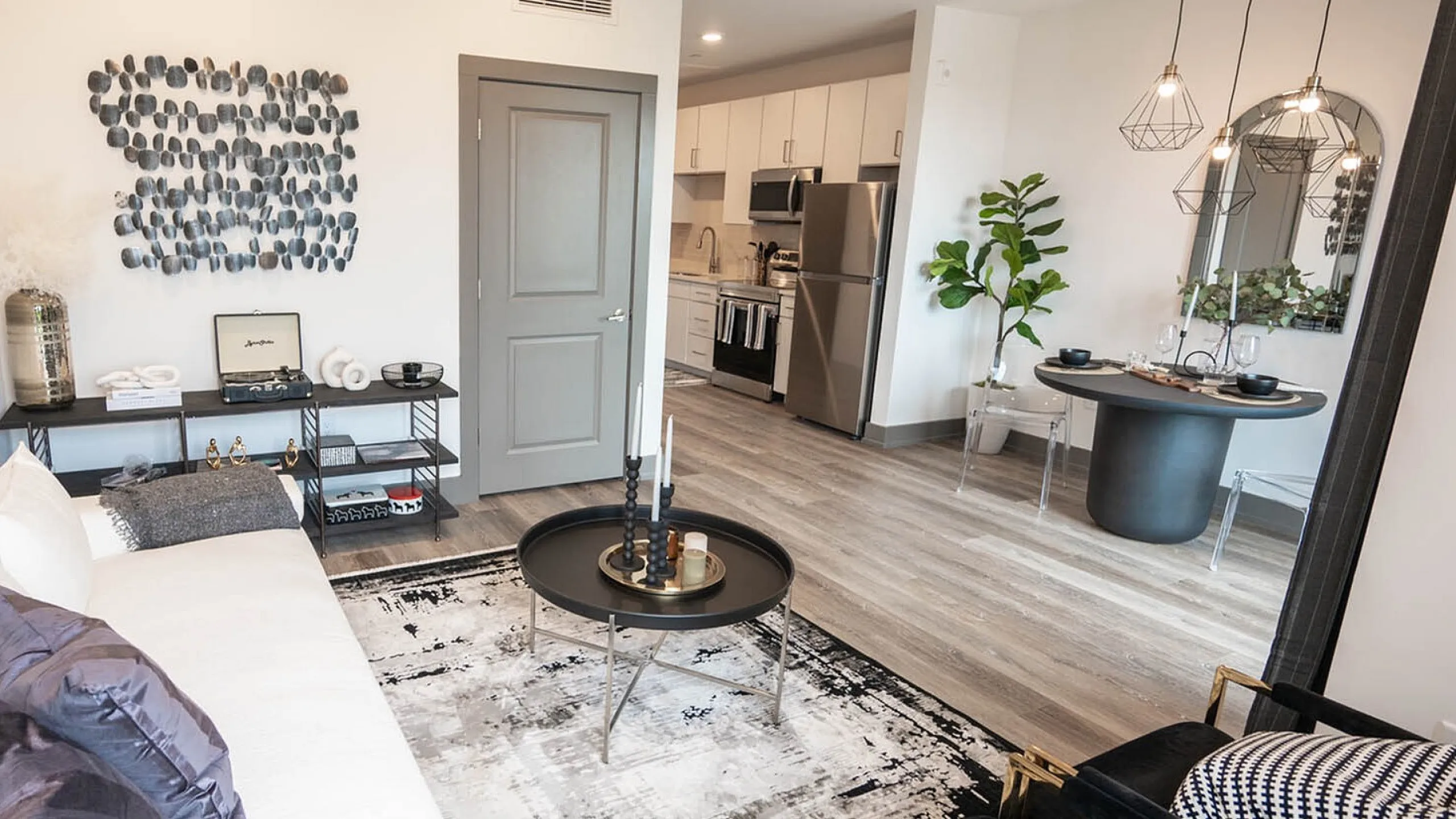Modern open-concept living and dining area with stylish decor, abstract wall art, and sleek kitchen appliances.