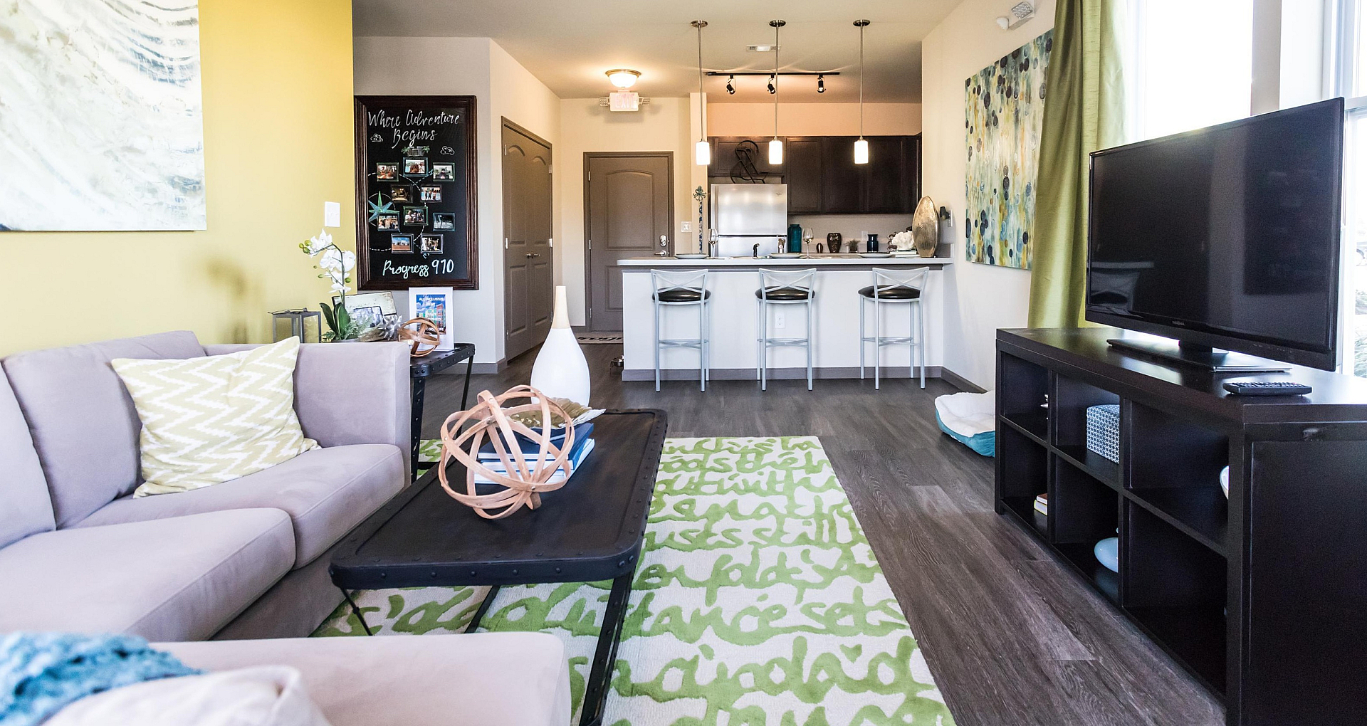 Bright and modern living room with stylish decor, open kitchen with bar seating, and large windows providing ample natural light.