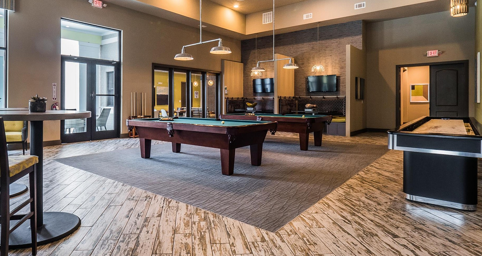 Spacious recreational lounge with modern pool tables, stylish seating, and contemporary lighting, perfect for entertaining or relaxing.