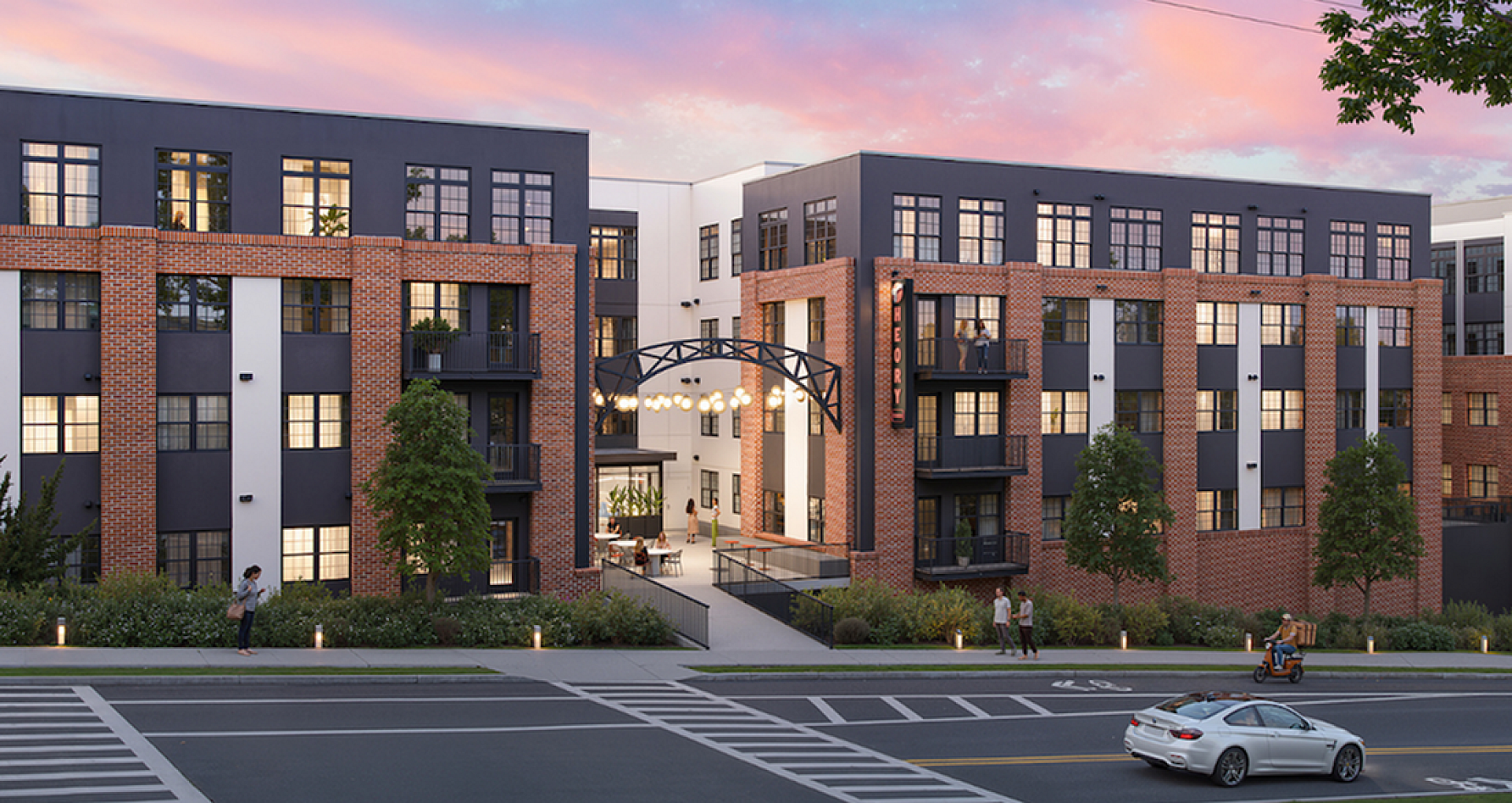 Charming urban apartment complex exterior at sunset, featuring modern design with brick and neutral tones, surrounded by lush greenery.