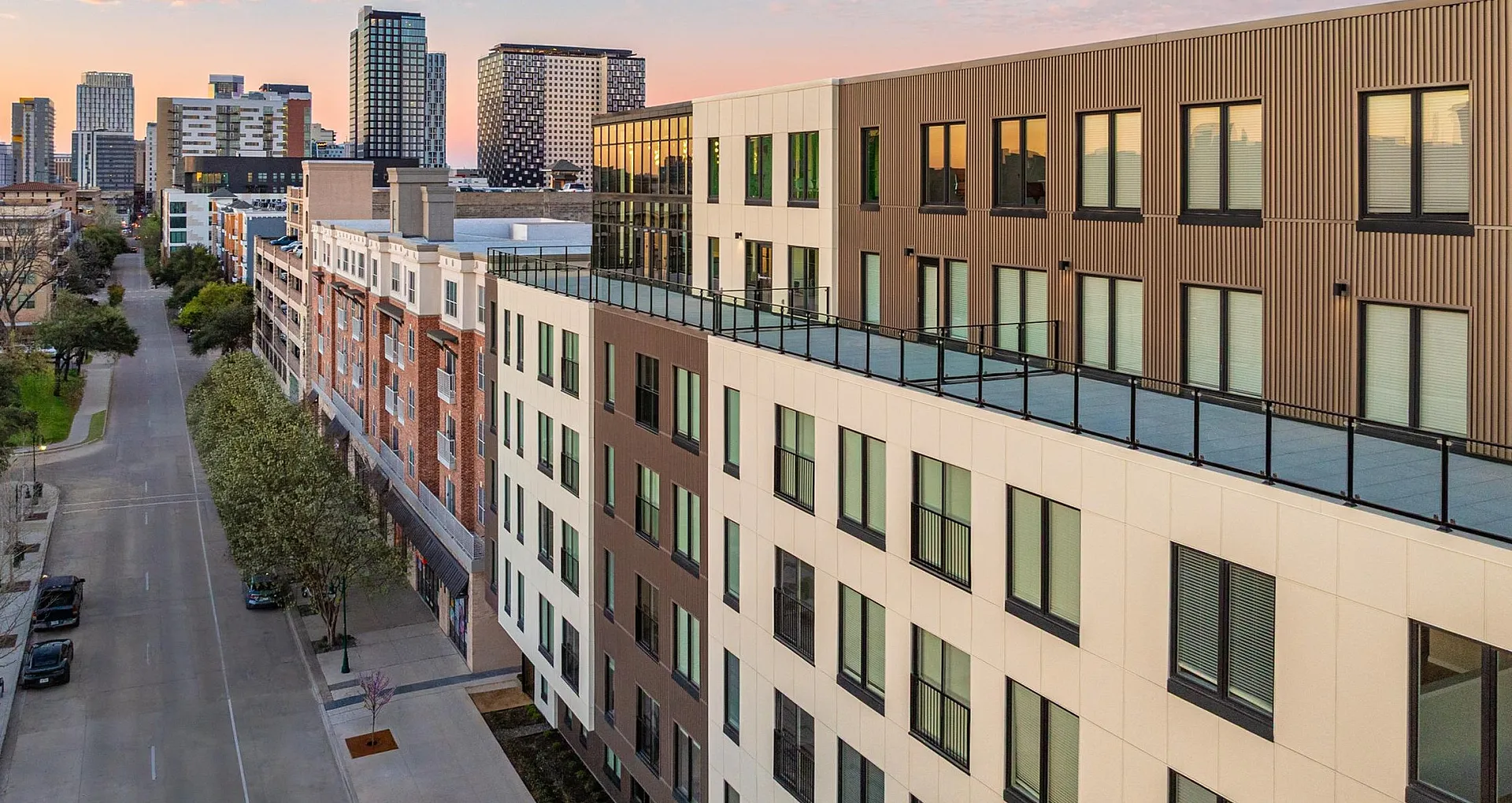 Modern urban apartment building with sleek design and expansive rooftop views, set against a vibrant city skyline.