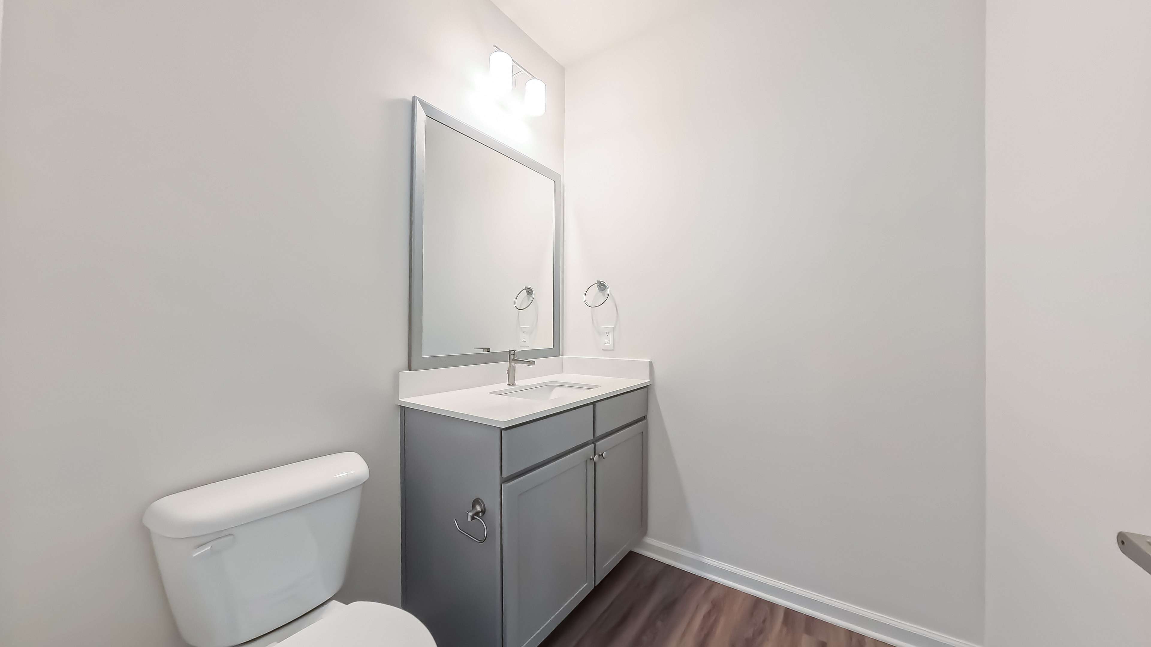 Modern bathroom with sleek gray vanity, large mirror, and elegant lighting. Bright and inviting atmosphere.