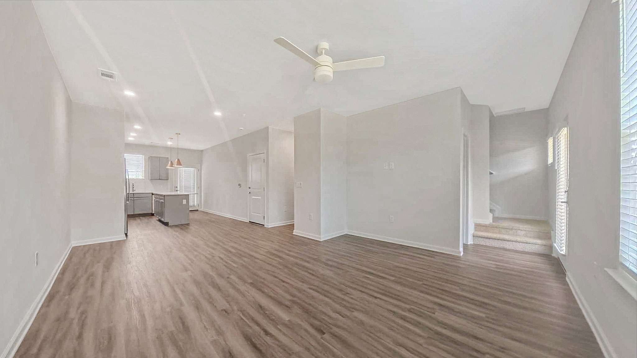 Bright open-concept living room with modern kitchen, elegant wood flooring, and abundant natural light.