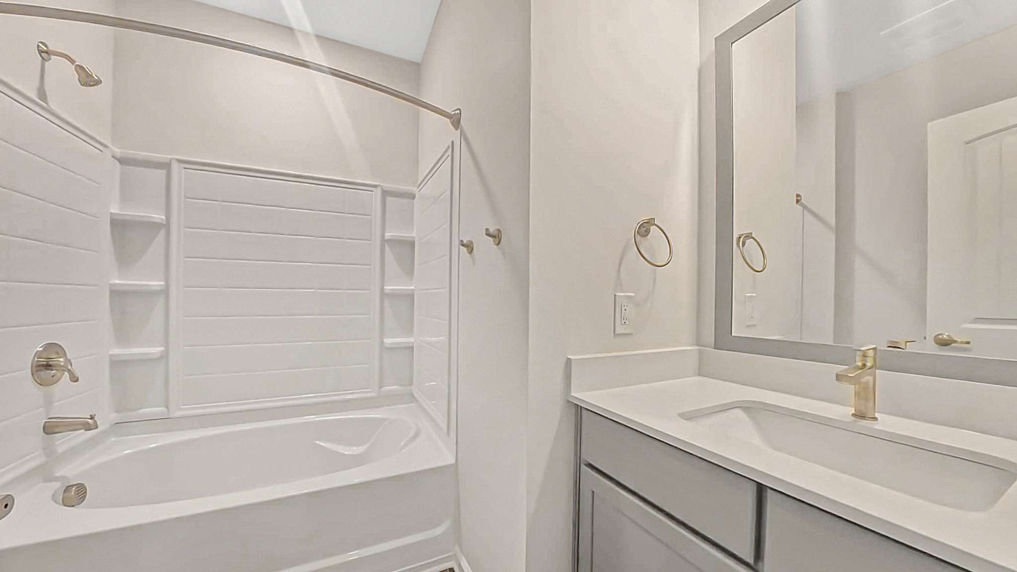 Elegant modern bathroom with a spacious bathtub, sleek white vanity, and large mirror, offering a serene and luxurious retreat.