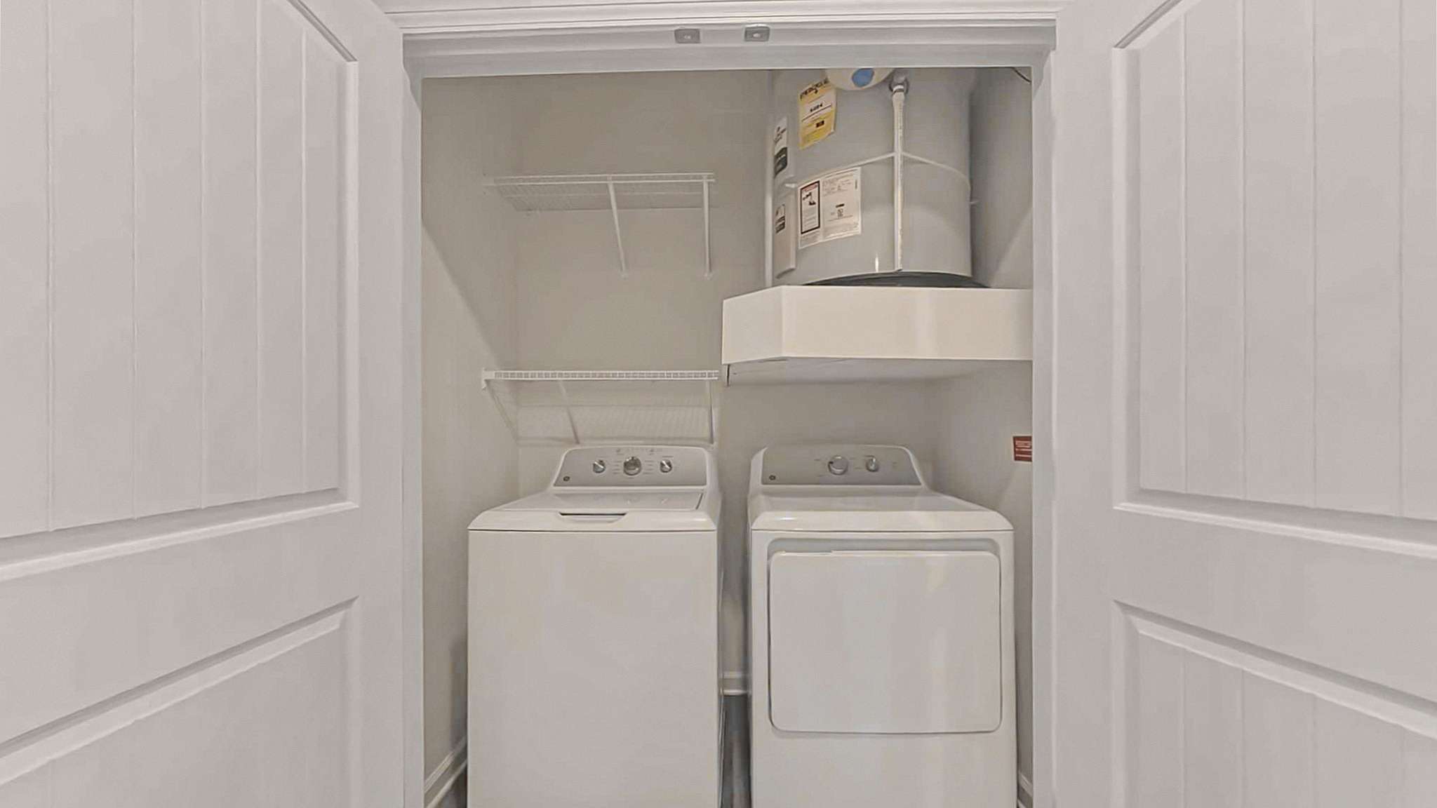 Modern apartment laundry closet featuring a sleek washer and dryer set, with ample shelving space for storage.