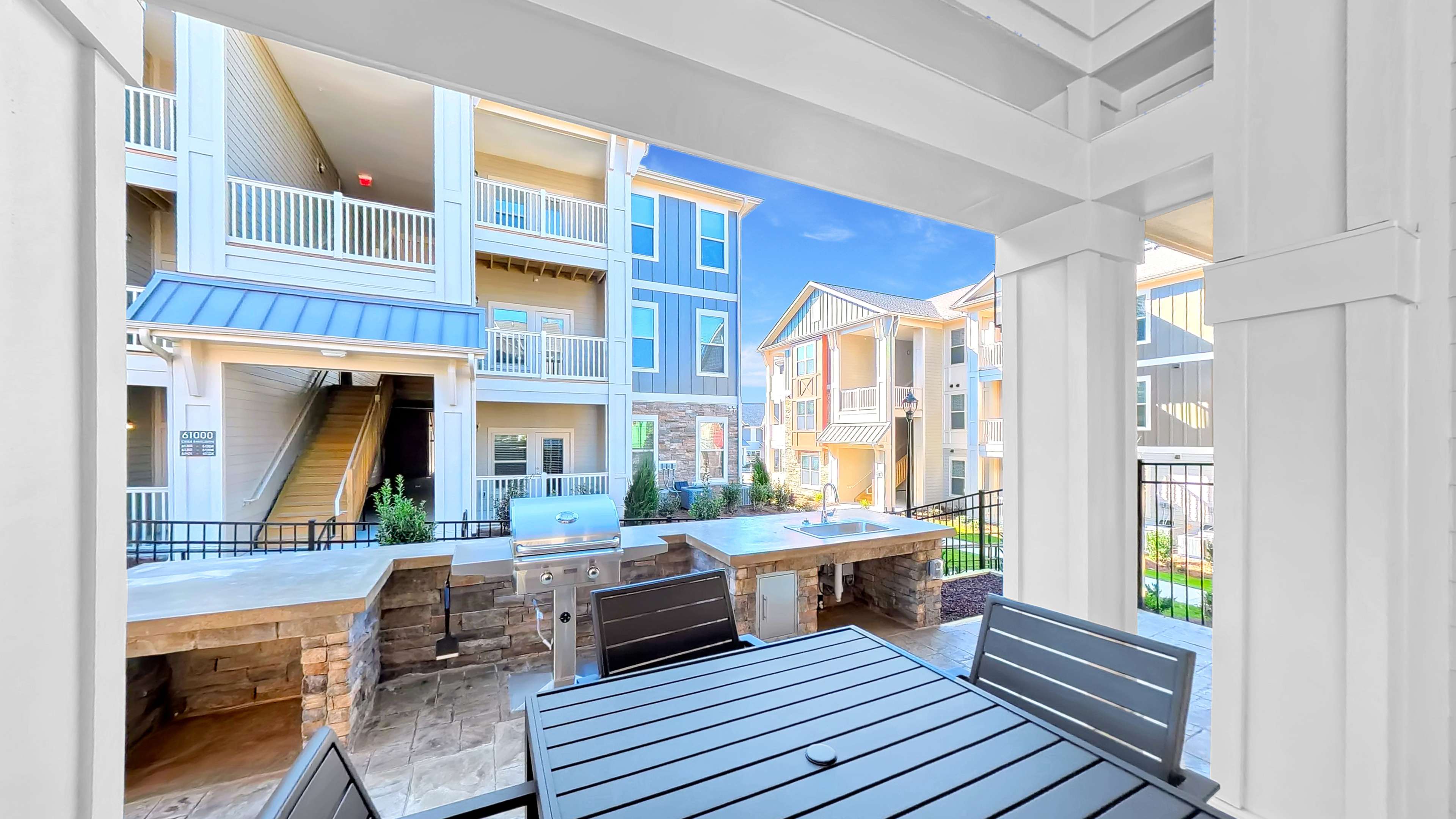 Charming apartment courtyard with modern grills and outdoor dining area, surrounded by elegant multi-story buildings with stylish balconies.