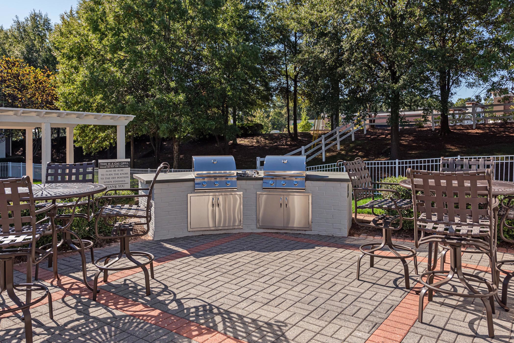 Inviting outdoor patio with sleek grills and stylish seating, surrounded by lush greenery.