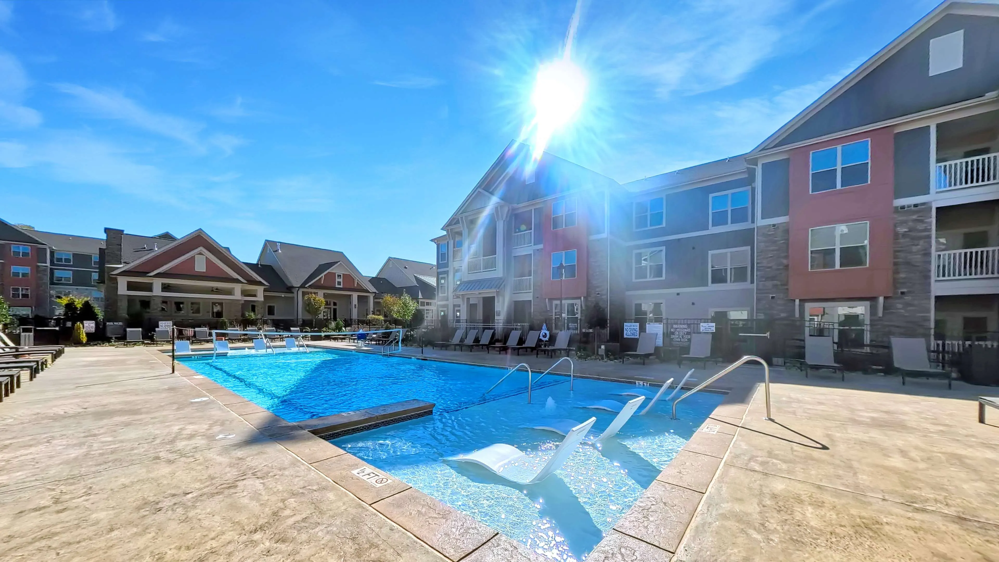 Charming apartment complex with a luxurious outdoor pool, sun-drenched lounge chairs, and modern architecture, perfect for relaxing and entertaining.