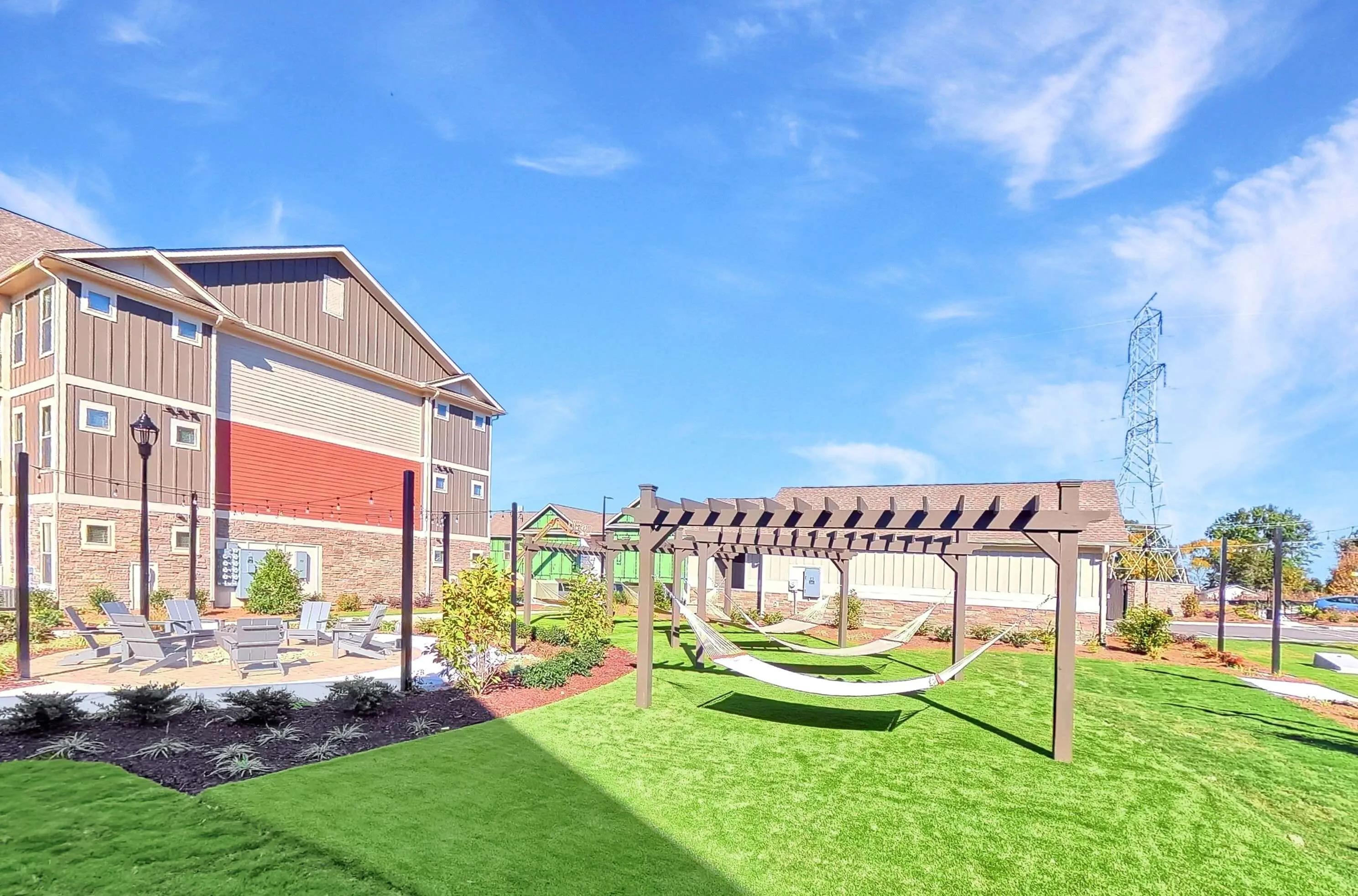 Charming outdoor area featuring modern pergola, relaxing hammocks, and cozy seating, set against a beautiful, well-maintained apartment complex.