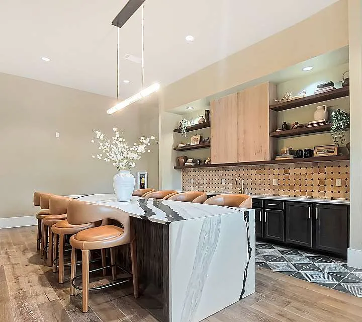 Luxurious kitchen with elegant marble island, cozy bar seating, and modern pendant lighting, perfect for entertaining.