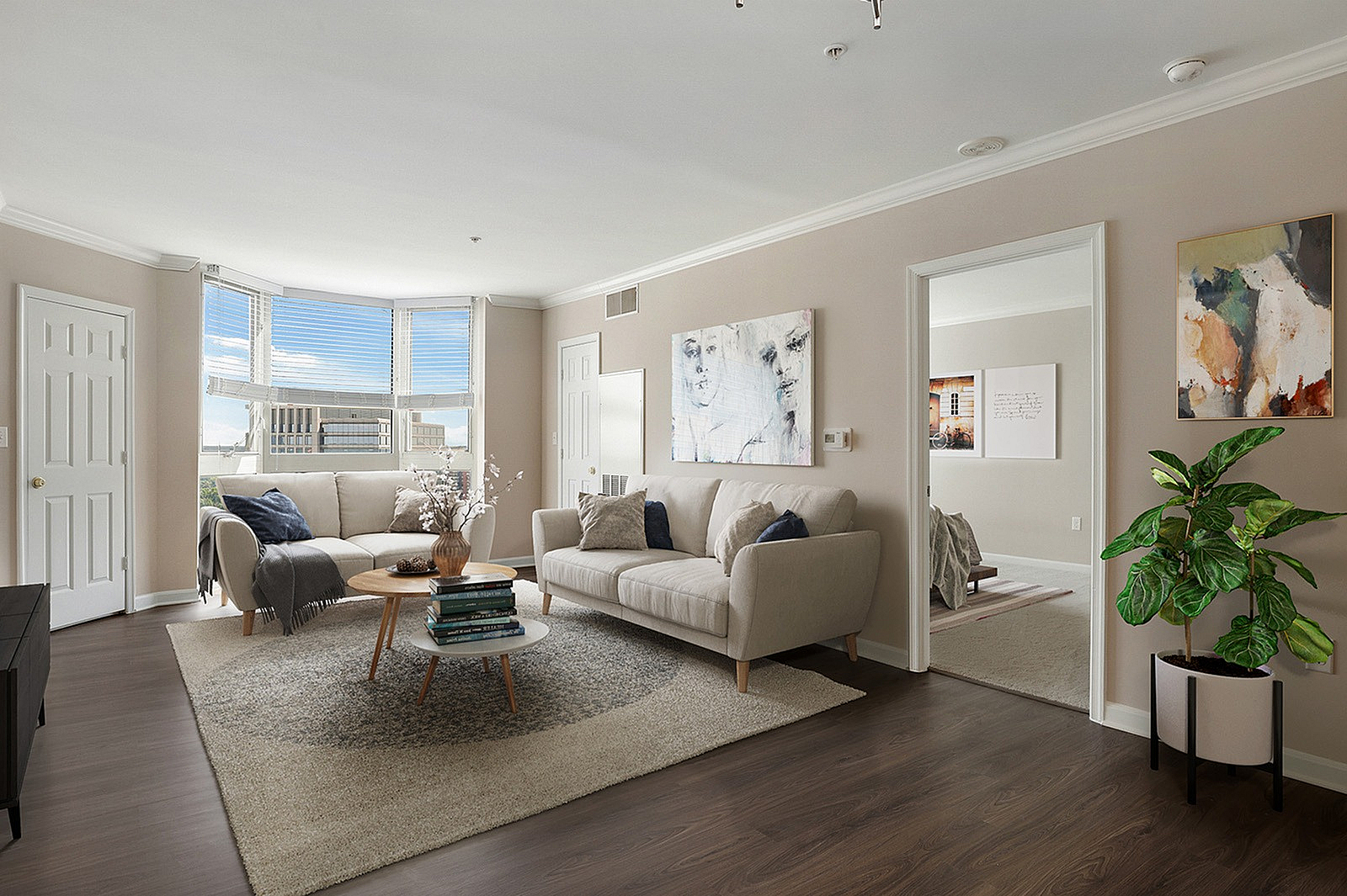 Inviting living room with modern decor, featuring a cozy beige sofa, stylish coffee table, and large bay windows offering natural light and scenic views.