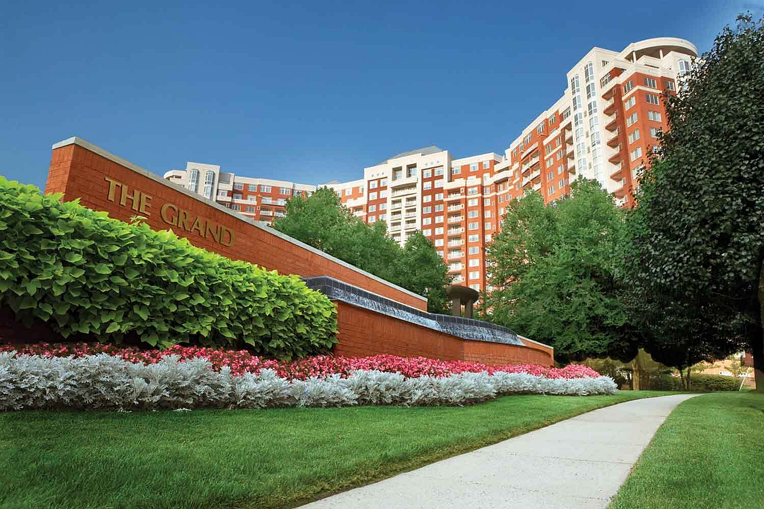 Luxurious apartment complex 'The Grand' showcasing stunning architecture, lush gardens, and sophisticated urban living.