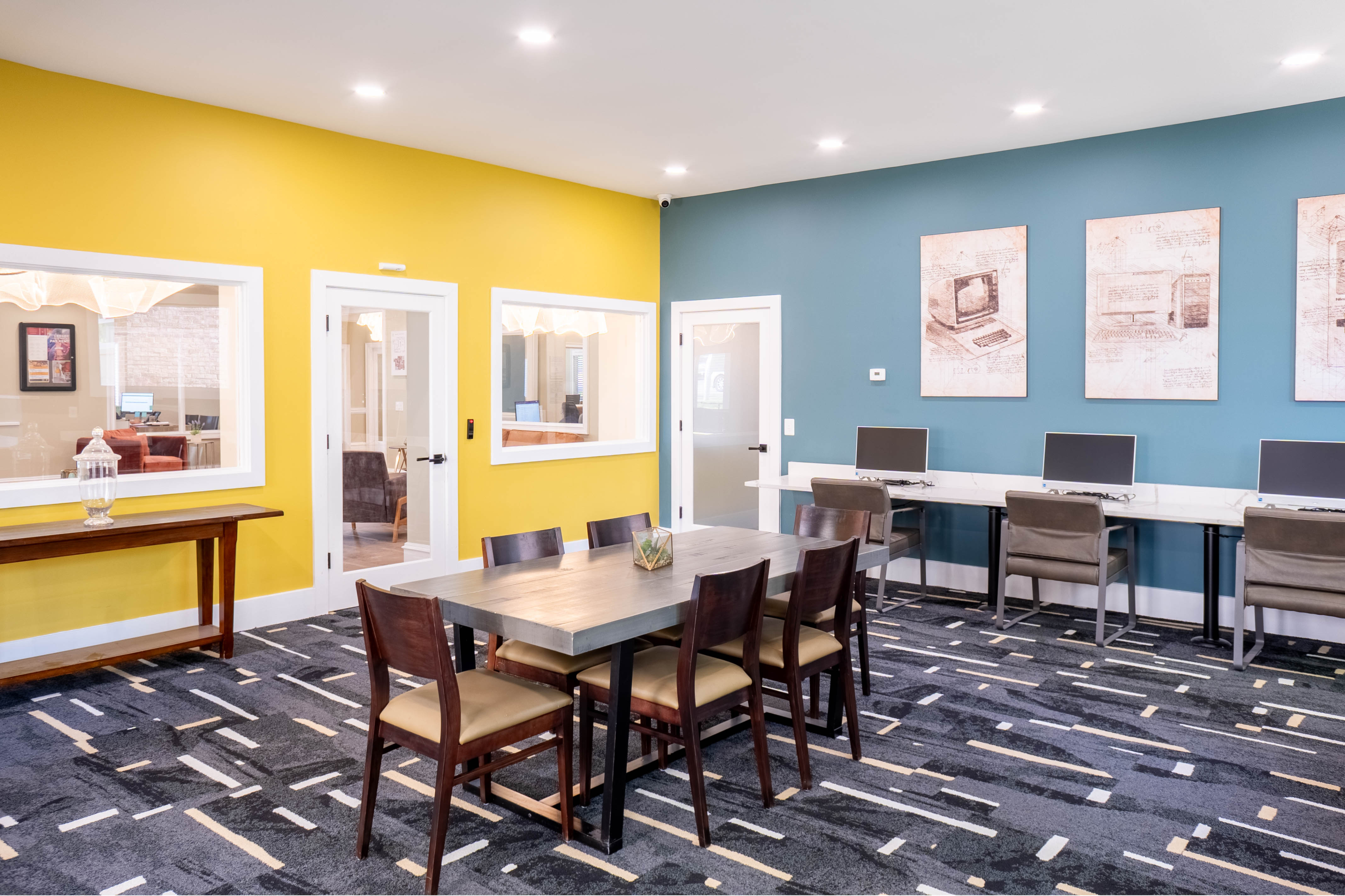 Vibrant office space featuring a modern communal table and workstations, highlighted by bold yellow and teal accent walls.