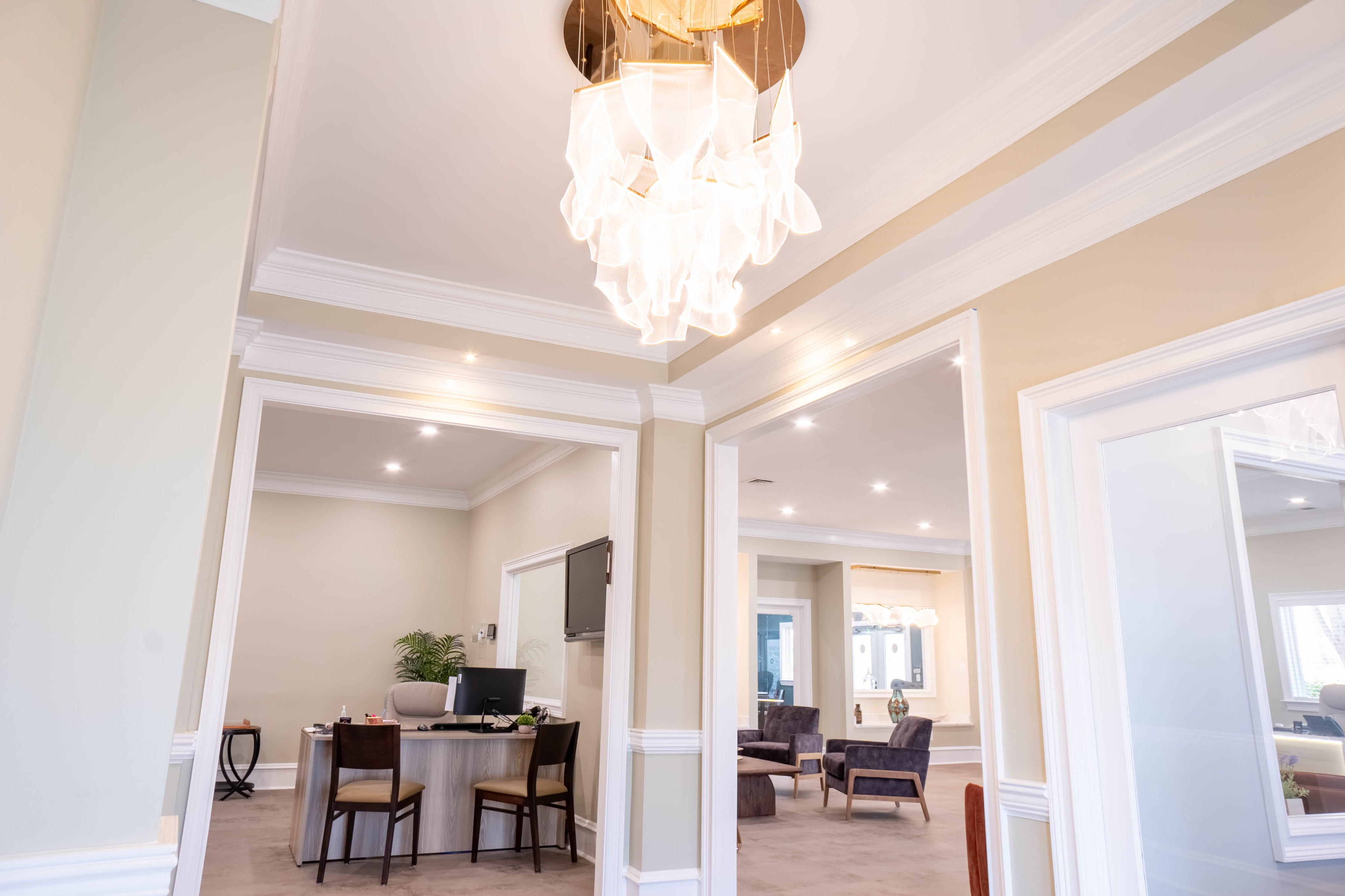 Elegant office space featuring a bright chandelier, modern furnishings, and an inviting lounge area.