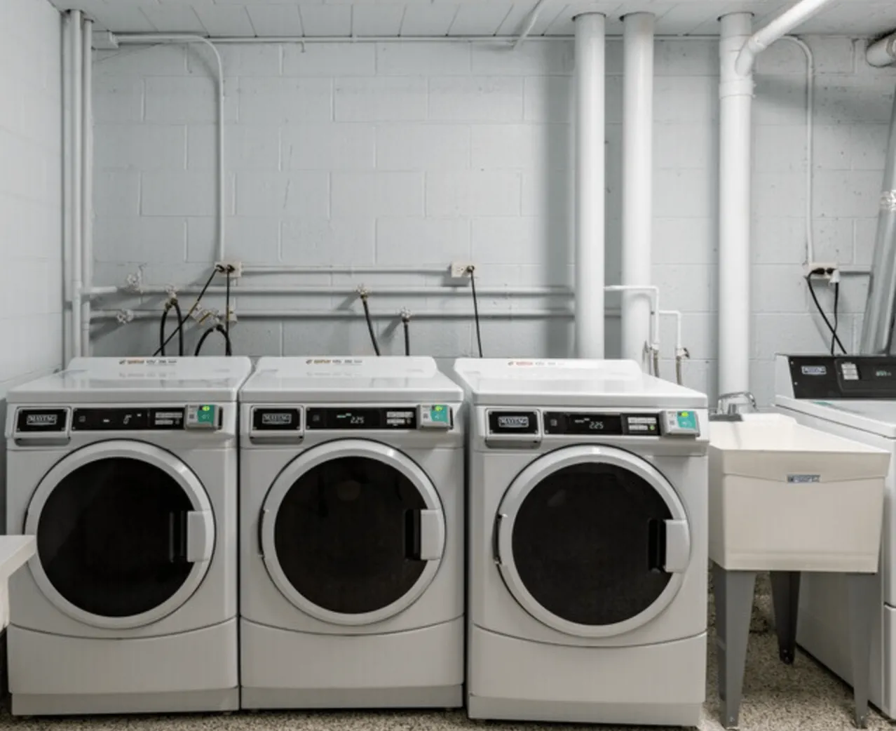 Modern laundry room featuring high-efficiency washers and dryers, bright and well-organized for convenient use.