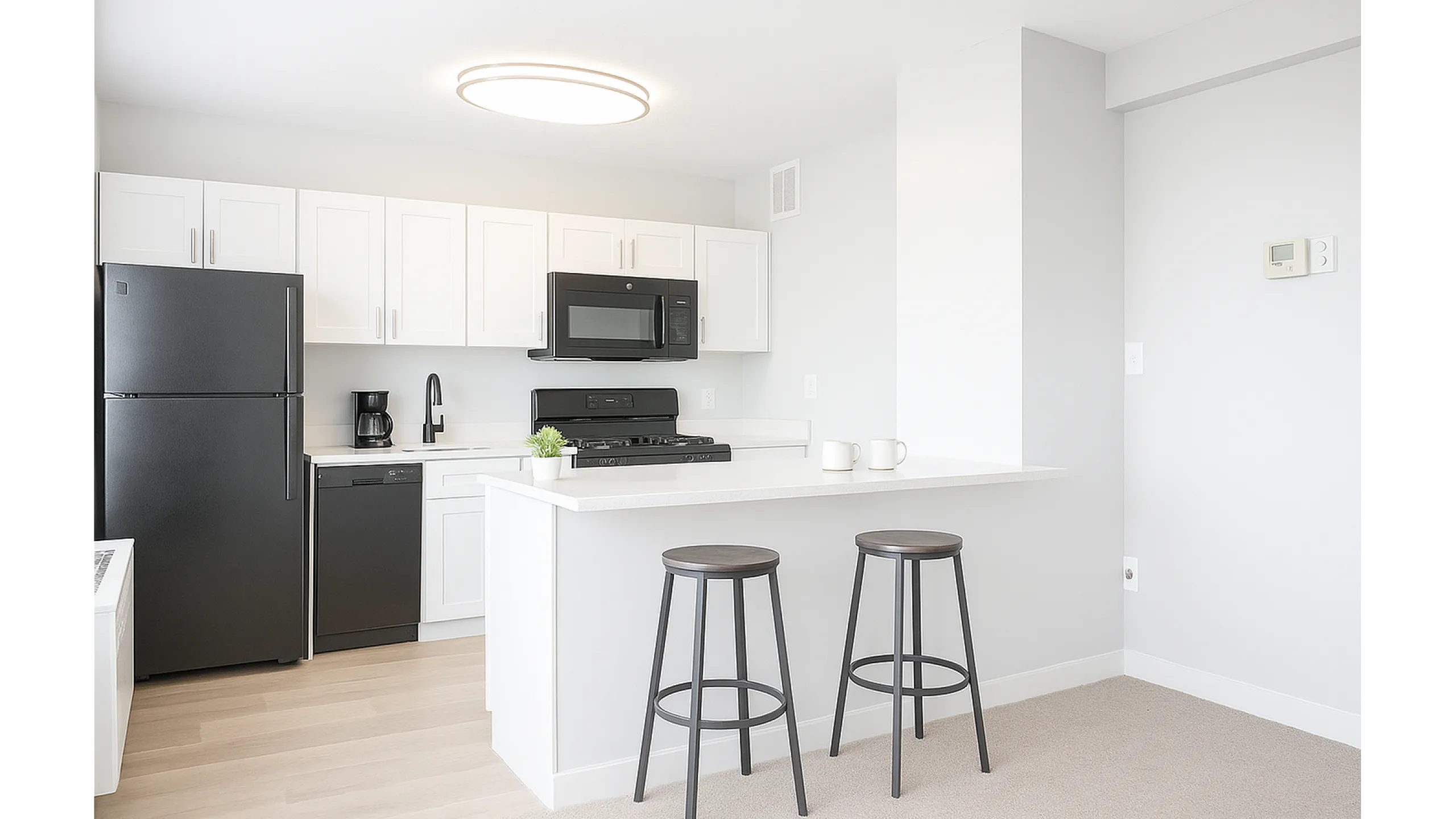 Modern kitchen with sleek countertops, stylish stools, and abundant natural light.