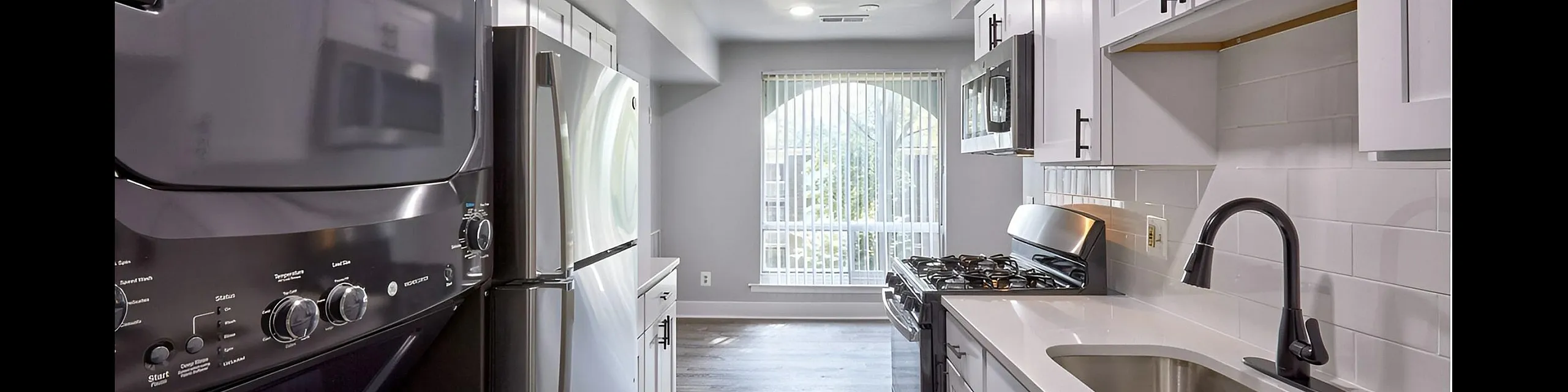 Sleek modern kitchen with stainless steel appliances, elegant white cabinetry, and a large window illuminating the space.