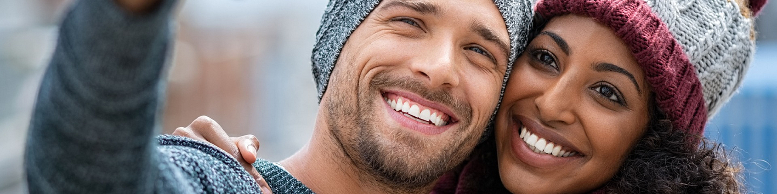 Joyful couple enjoying a moment together, bundled up in cozy winter hats and sweaters.