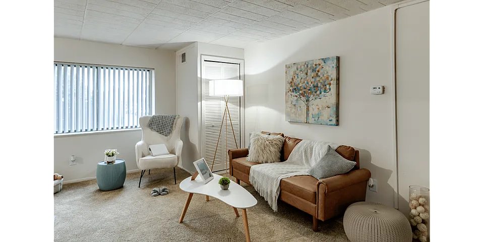 Cozy living room with stylish decor, featuring a plush sofa, modern armchair, artistic painting, and ambient lighting.
