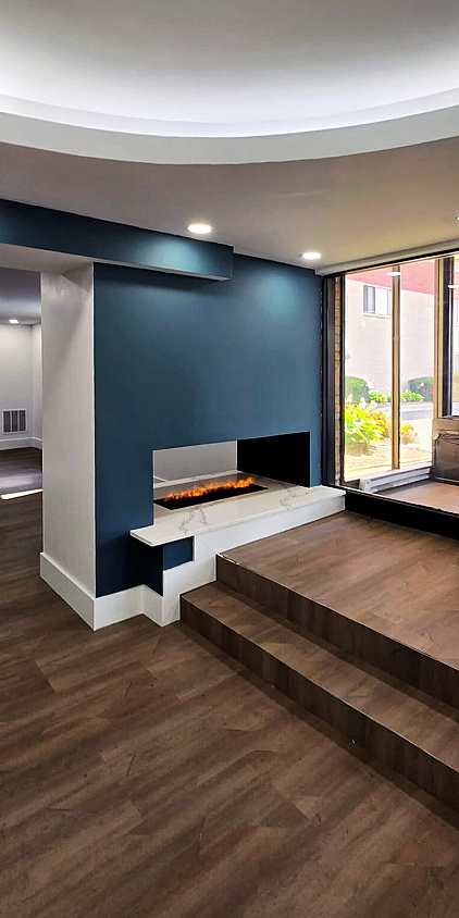 Modern apartment interior featuring a stylish fireplace, elegant wood flooring, and expansive windows offering natural light.