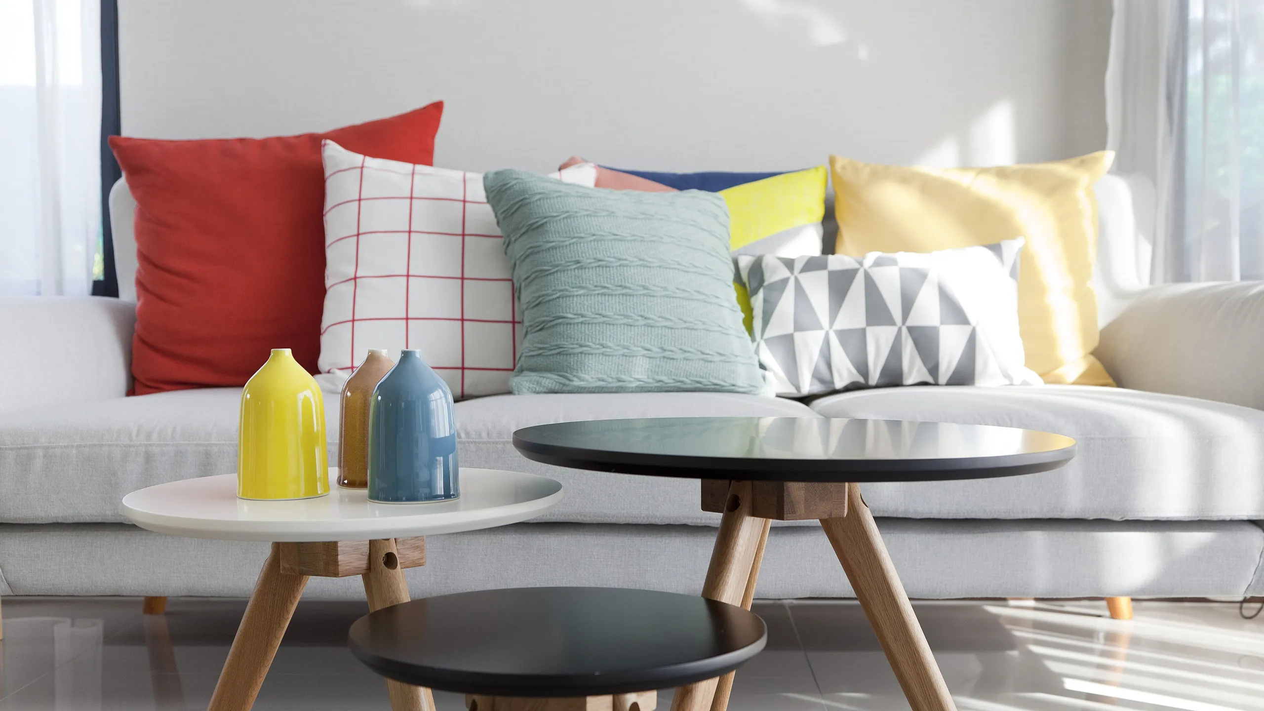 Modern living room with vibrant accent pillows and chic nesting tables, perfect for stylish comfort.