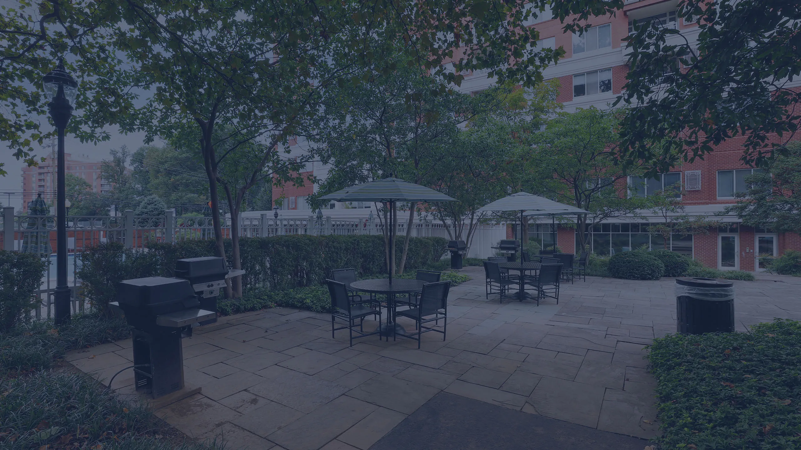 Charming outdoor patio area with elegant seating, shaded umbrellas, and modern grills, perfect for entertaining and relaxation amidst lush greenery.