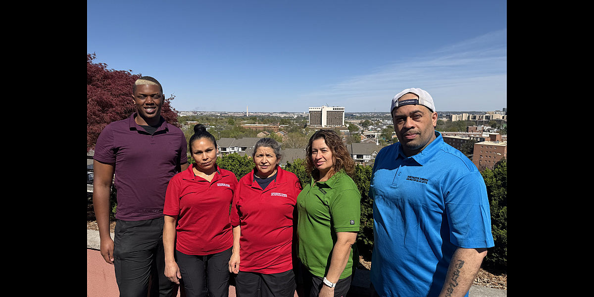 Group of five smiling individuals standing in front of a scenic cityscape, showcasing a vibrant community atmosphere.