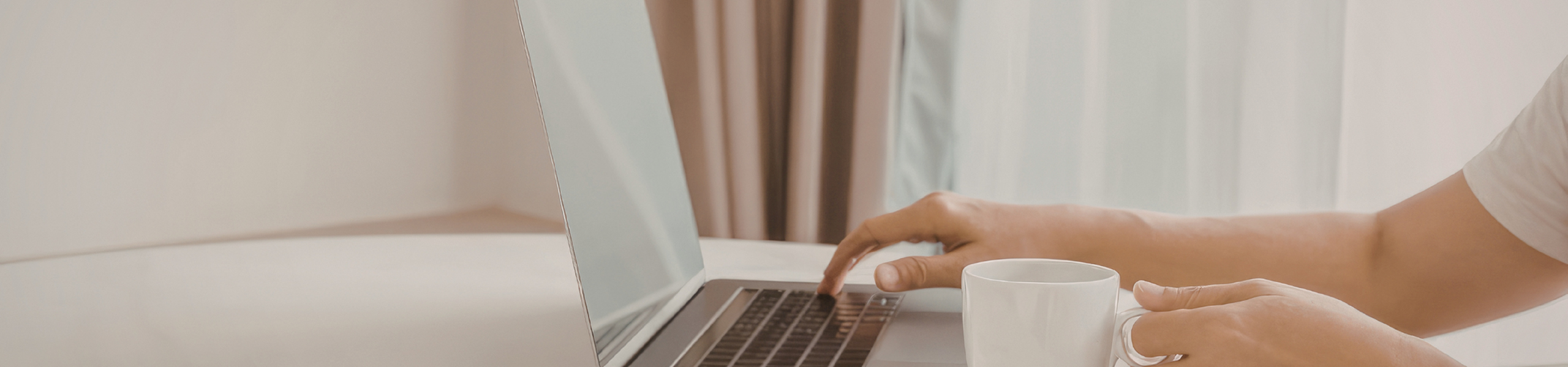 FAQ Banner Image Person on Laptop holding coffee mug