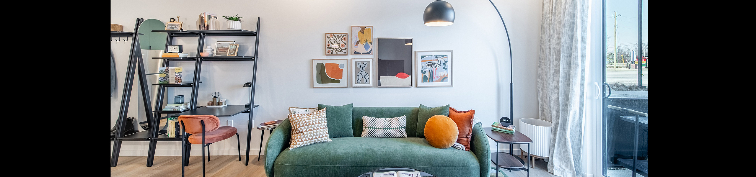 Bright and modern living room featuring a stylish green sofa, colorful cushions, and artistic wall decor, with natural light pouring in through a sliding glass door.