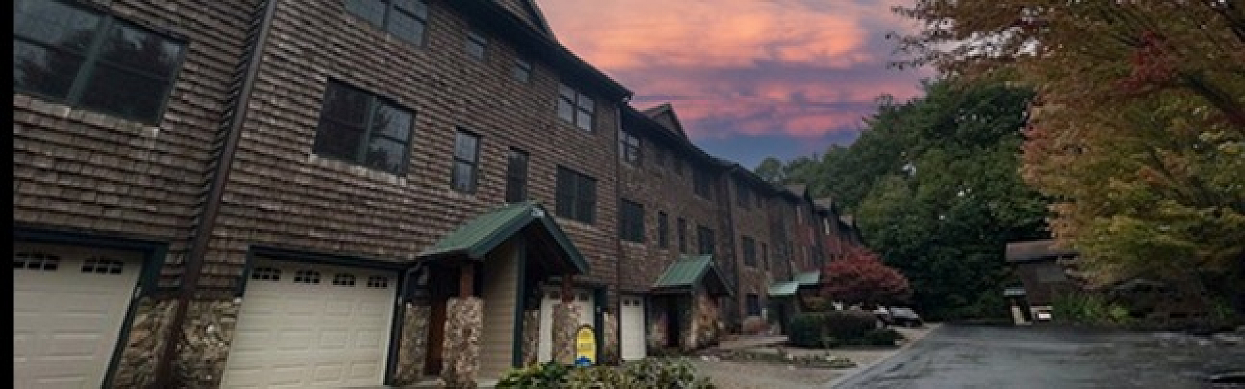 Charming townhouse neighborhood with rustic wooden facade, nestled in a serene neighborhood with stunning sunset skies and lush greenery.