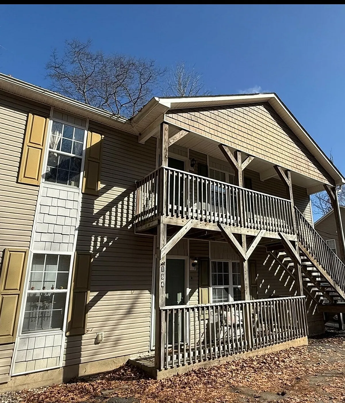 Charming two-story apartment building with wooden balconies, nestled in a serene natural setting, perfect for a tranquil lifestyle.