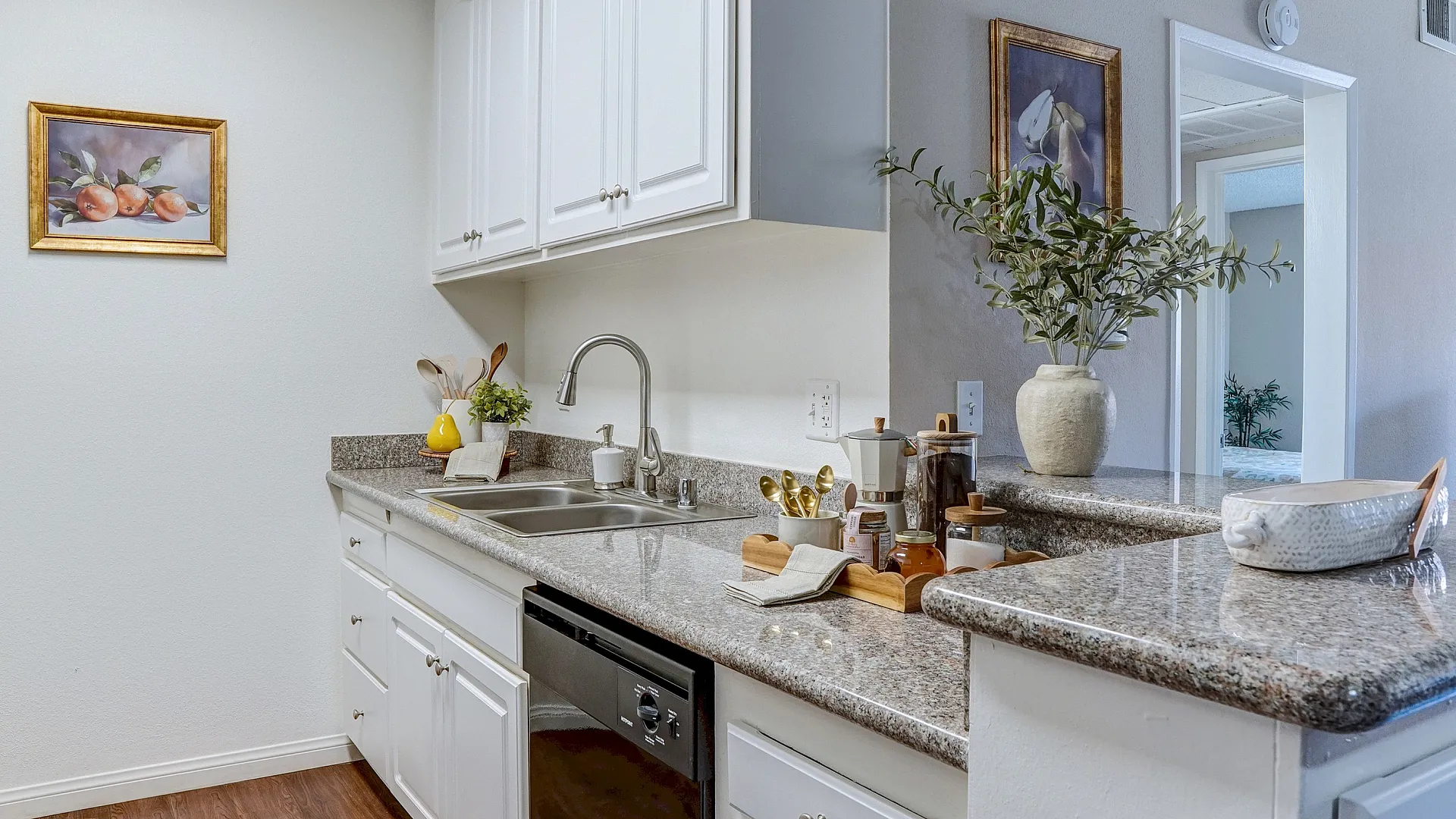 Charming kitchen with sleek white cabinetry, elegant granite countertops, and modern fixtures, adorned with stylish decor and natural accents.