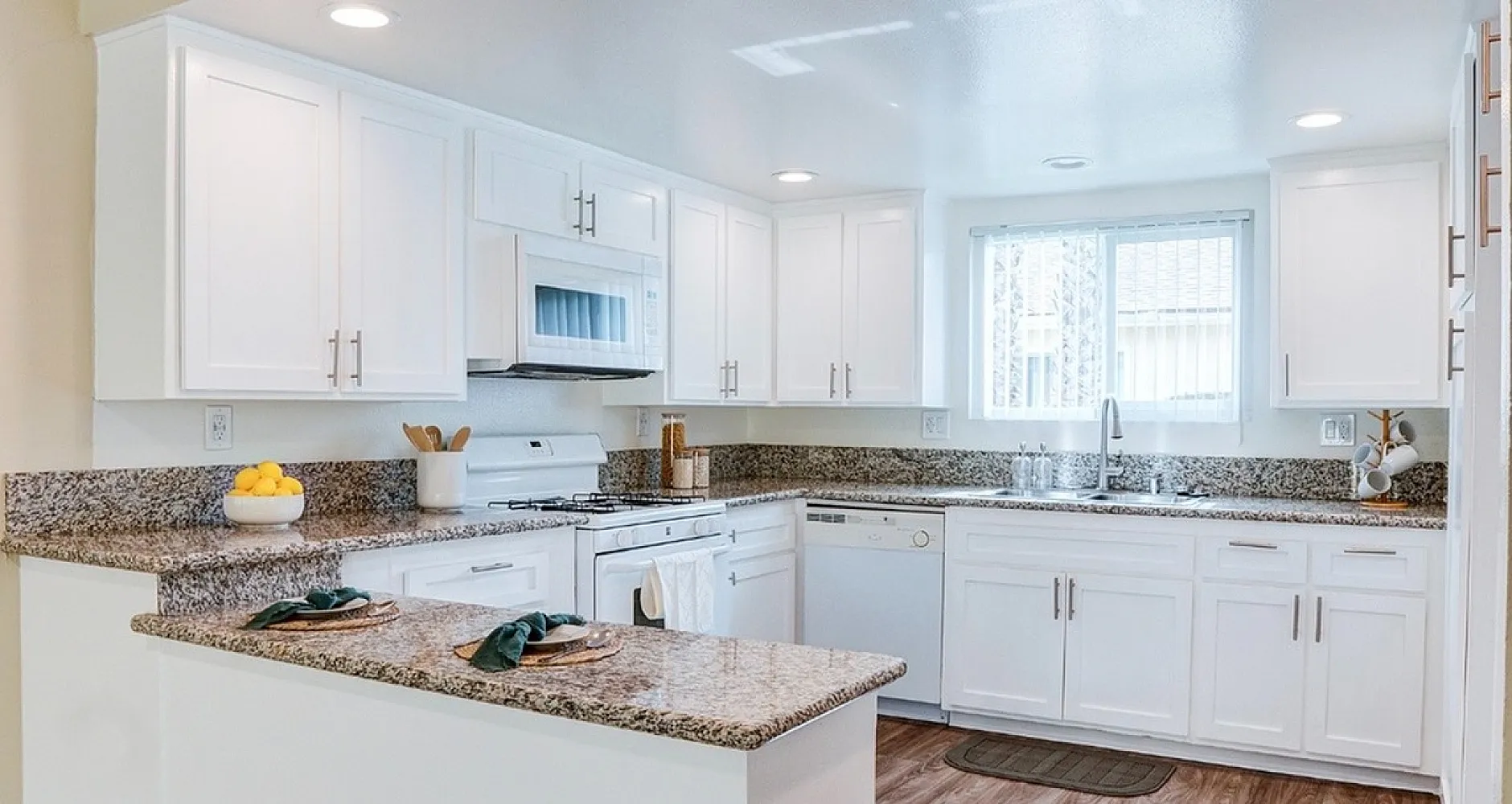 Bright, modern kitchen with granite countertops, sleek white cabinets, and stainless steel appliances, perfect for culinary enthusiasts.