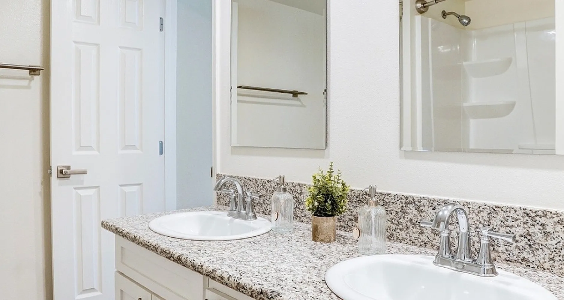 Elegant bathroom with granite countertops, dual sinks, and a modern shower area with sleek fixtures.