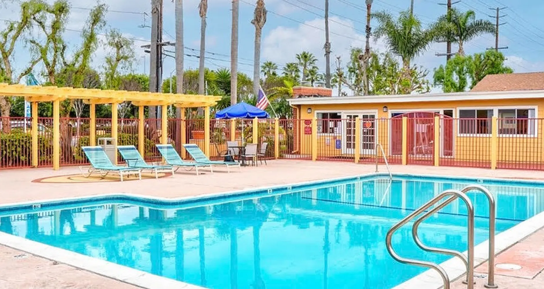Inviting outdoor pool area with sun loungers, surrounded by palm trees and vibrant landscaping, ideal for relaxation.