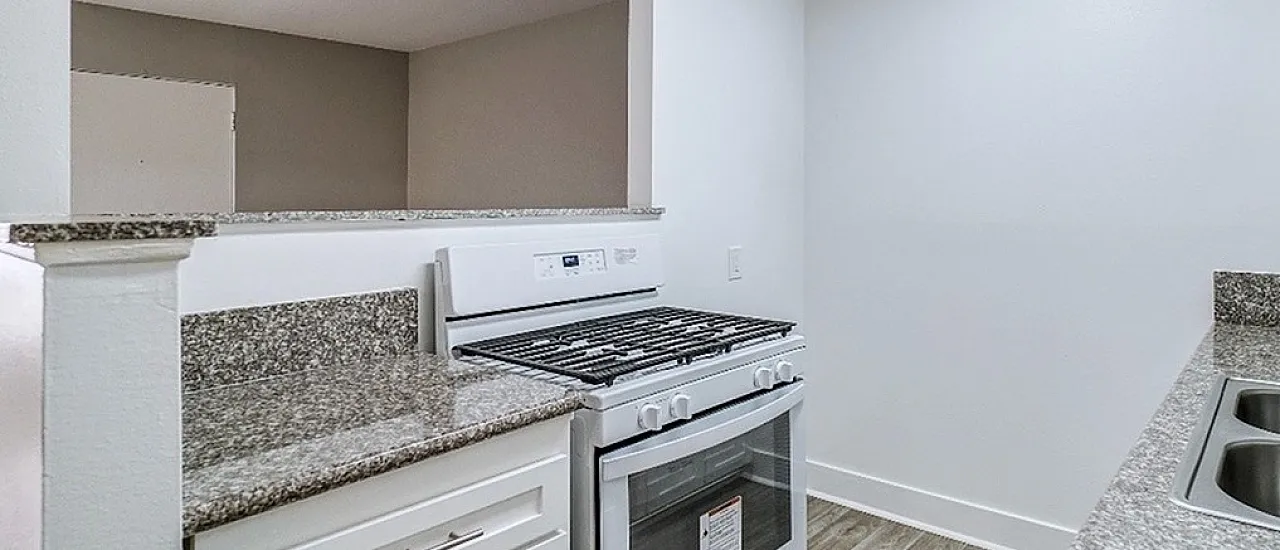 Modern kitchen with sleek granite countertops, white cabinetry, and stainless steel appliances, offering a bright and inviting cooking space.