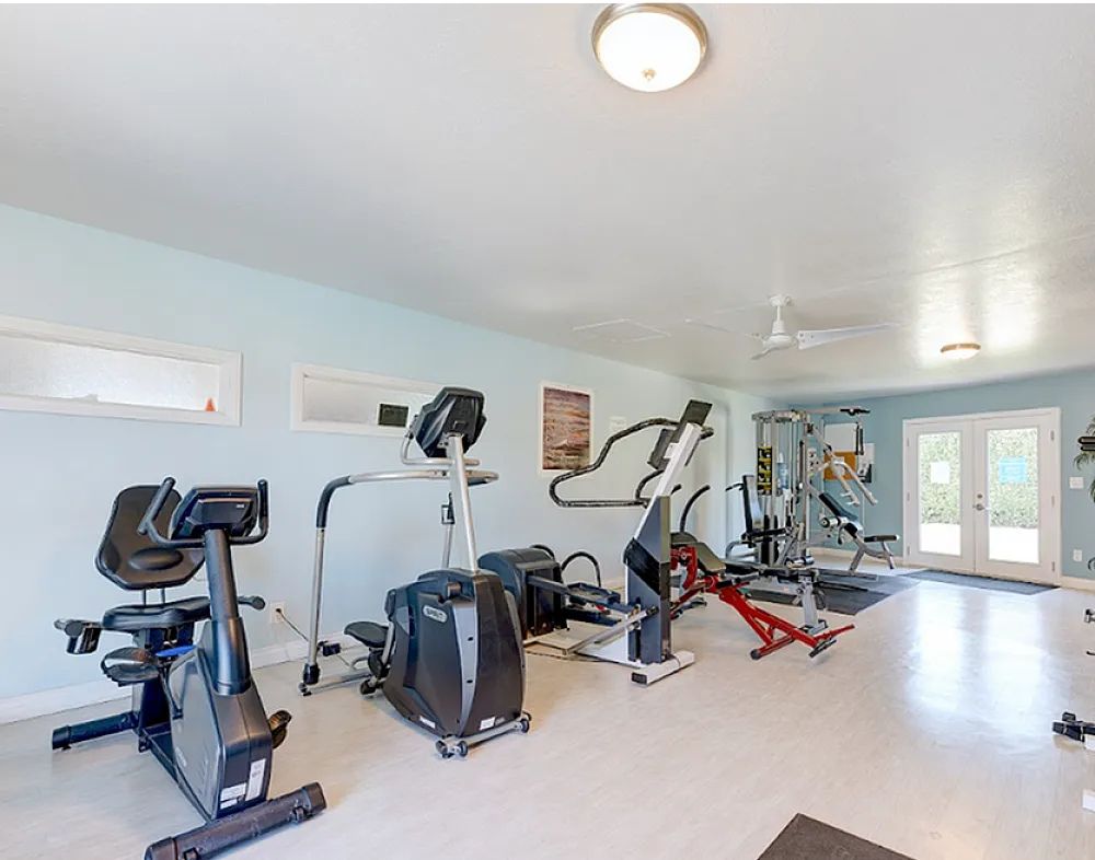 Bright and modern fitness room equipped with treadmills, stationary bikes, and weight machines, perfect for an invigorating workout experience.