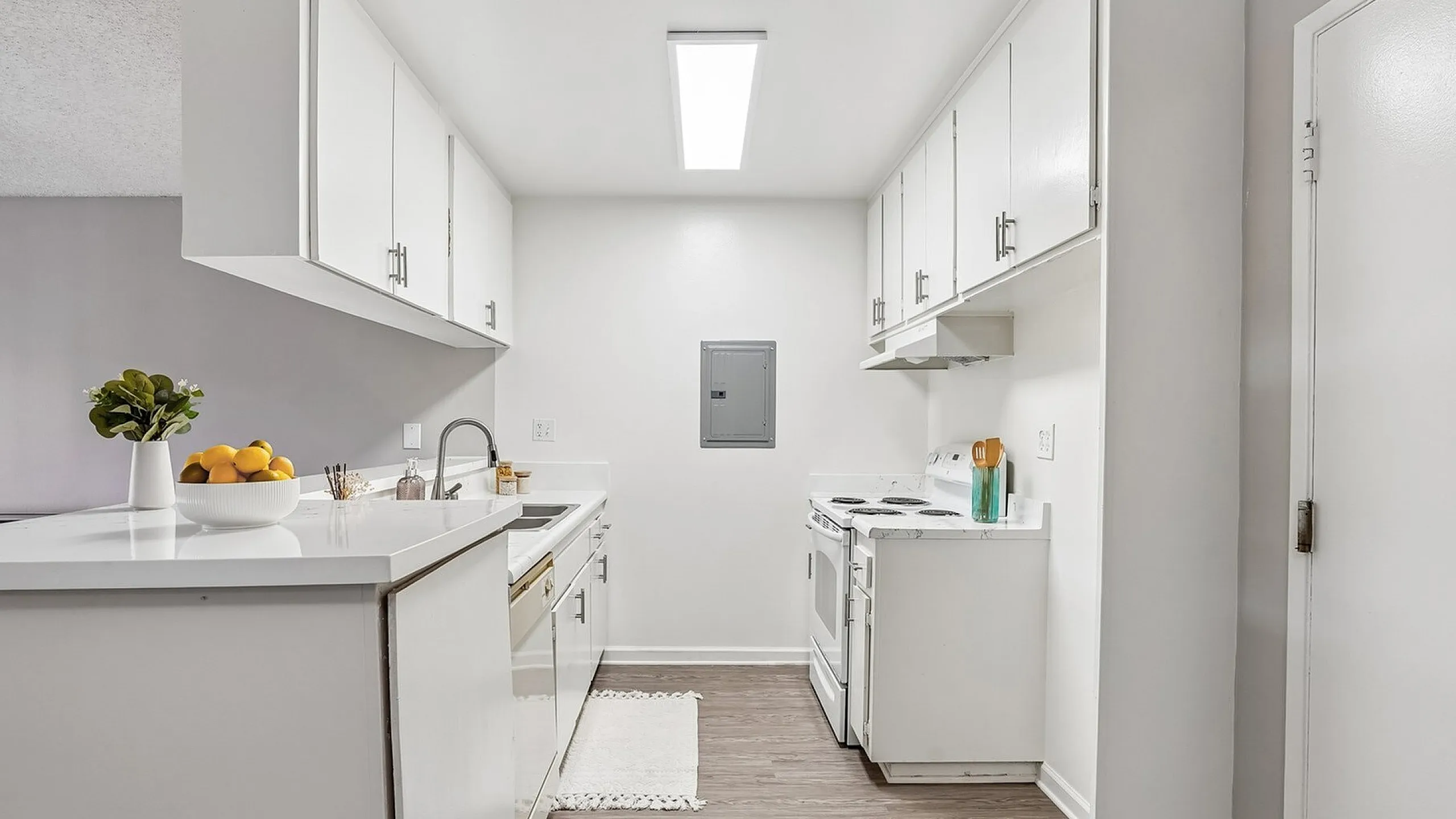 Bright and modern kitchen with sleek white cabinetry, stylish countertops, and warm wood flooring for an inviting atmosphere.