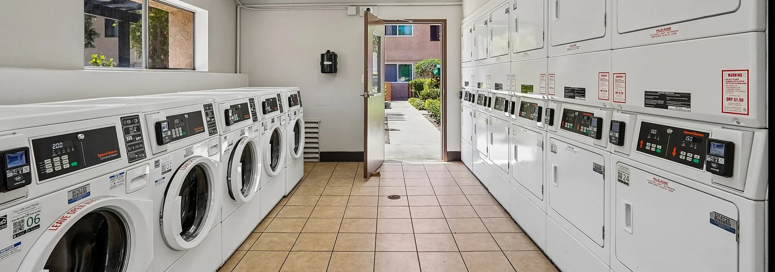 Modern laundry facility with multiple washers and dryers, ample natural light, and convenient location.