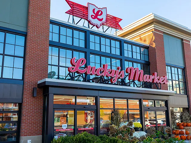Charming storefront of a market with a bright, inviting red sign and elegant brick architecture.