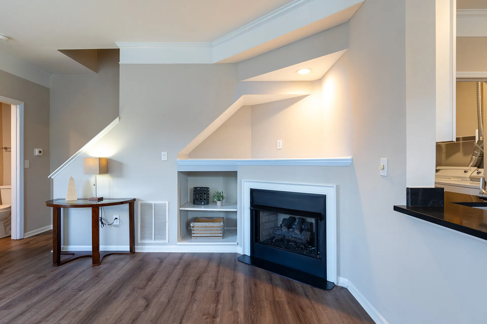 Charming living area with a cozy fireplace, elegant wood floors, and modern built-in shelving.