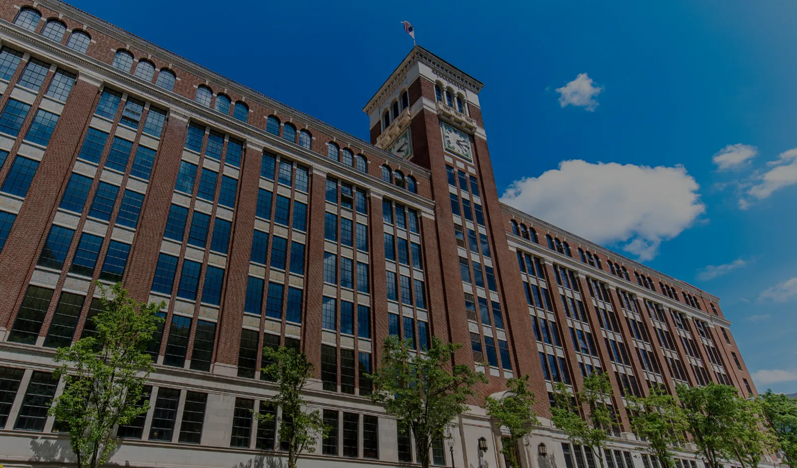 Magnificent historic building with stunning brick facade and large windows, crowned by a clock tower against a vibrant blue sky.