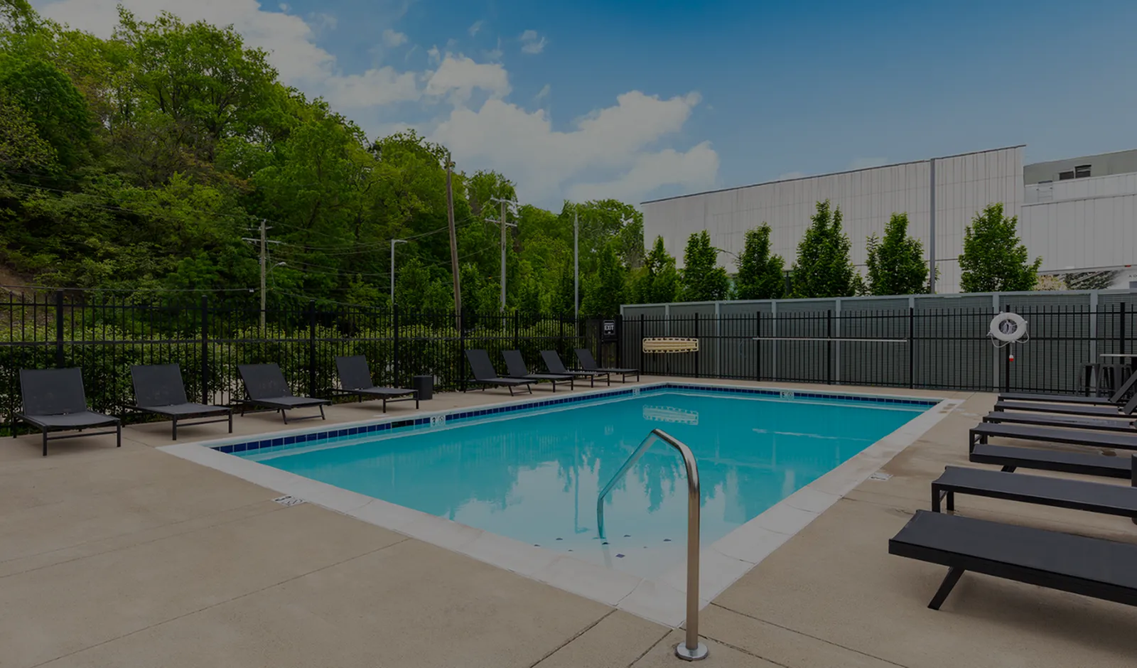 Inviting outdoor swimming pool with modern lounge chairs and lush greenery, perfect for relaxation and leisure.