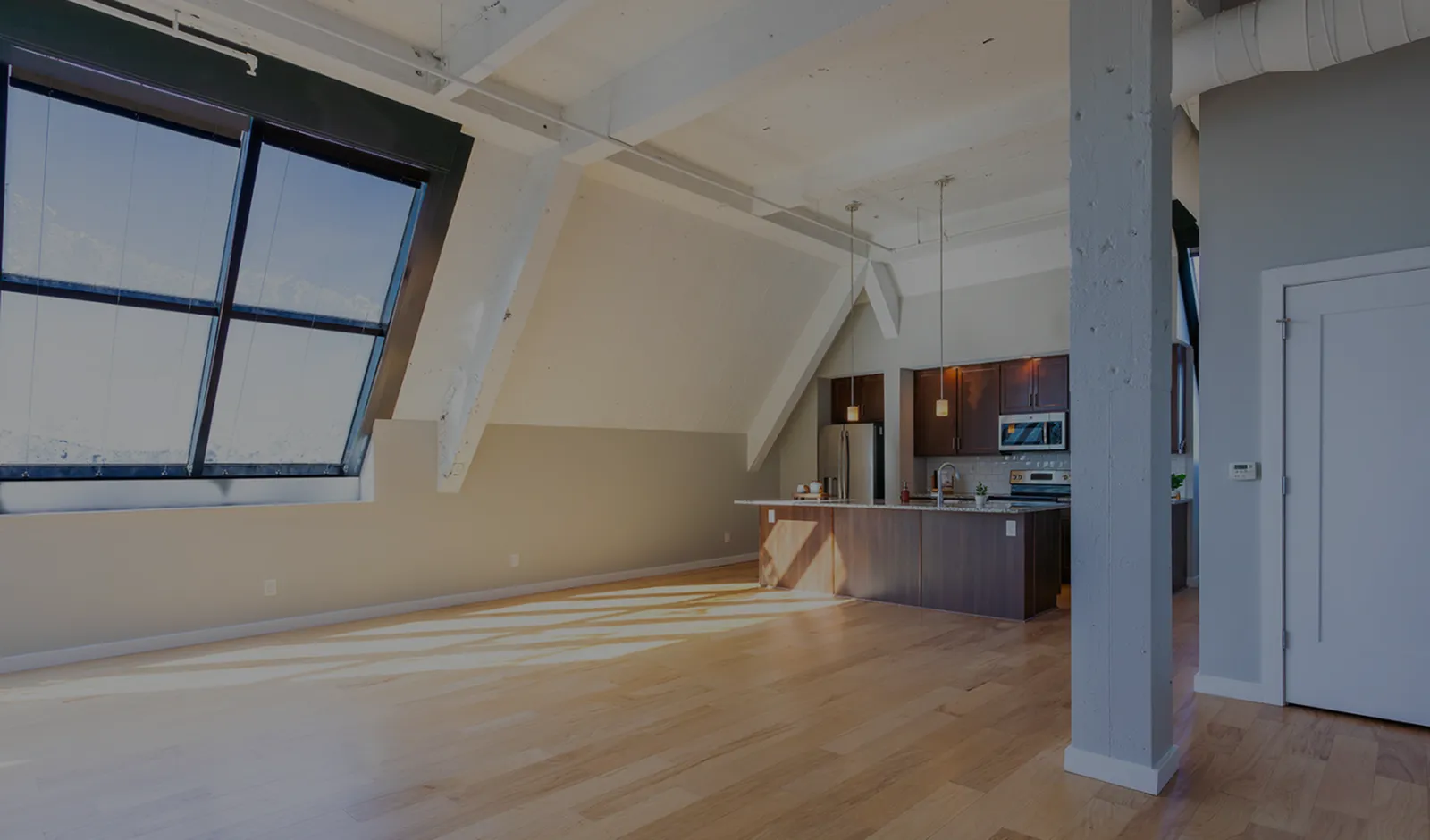 Bright loft apartment with large slanted windows, hardwood floors, and a modern kitchen island.