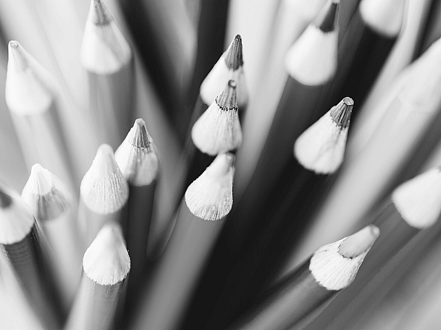 Dynamic close-up view of color pencils arranged in an artistic cluster, showcasing sharp tips and smooth surfaces in monochrome.
