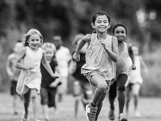 Joyful group of children running in a lush green field, capturing the essence of playfulness and freedom.