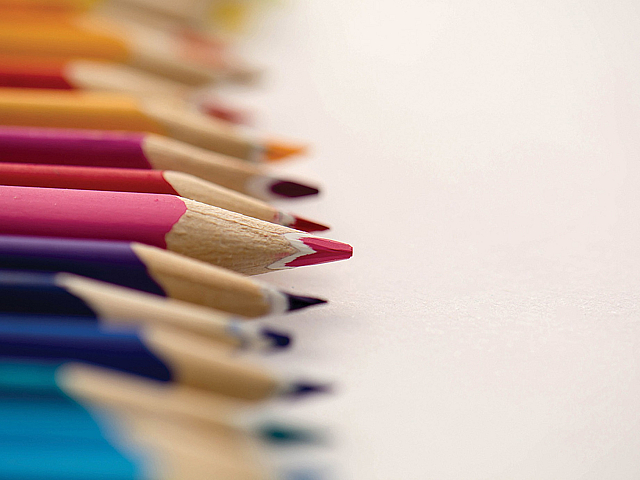 Vibrant array of colorful pencils aligned on a white surface, showcasing creativity and artistic potential.