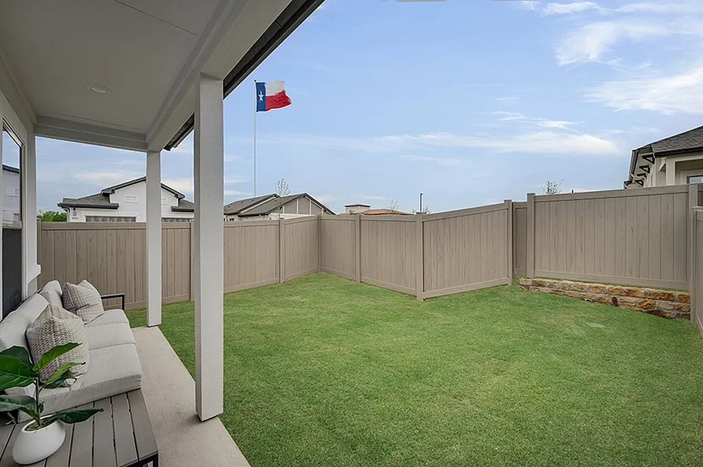 Luxe of Prosper | Apartments in McKinney | Rental in McKinney | Charming outdoor patio with cozy seating overlooking a lush green garden and modern fencing, perfect for relaxation.