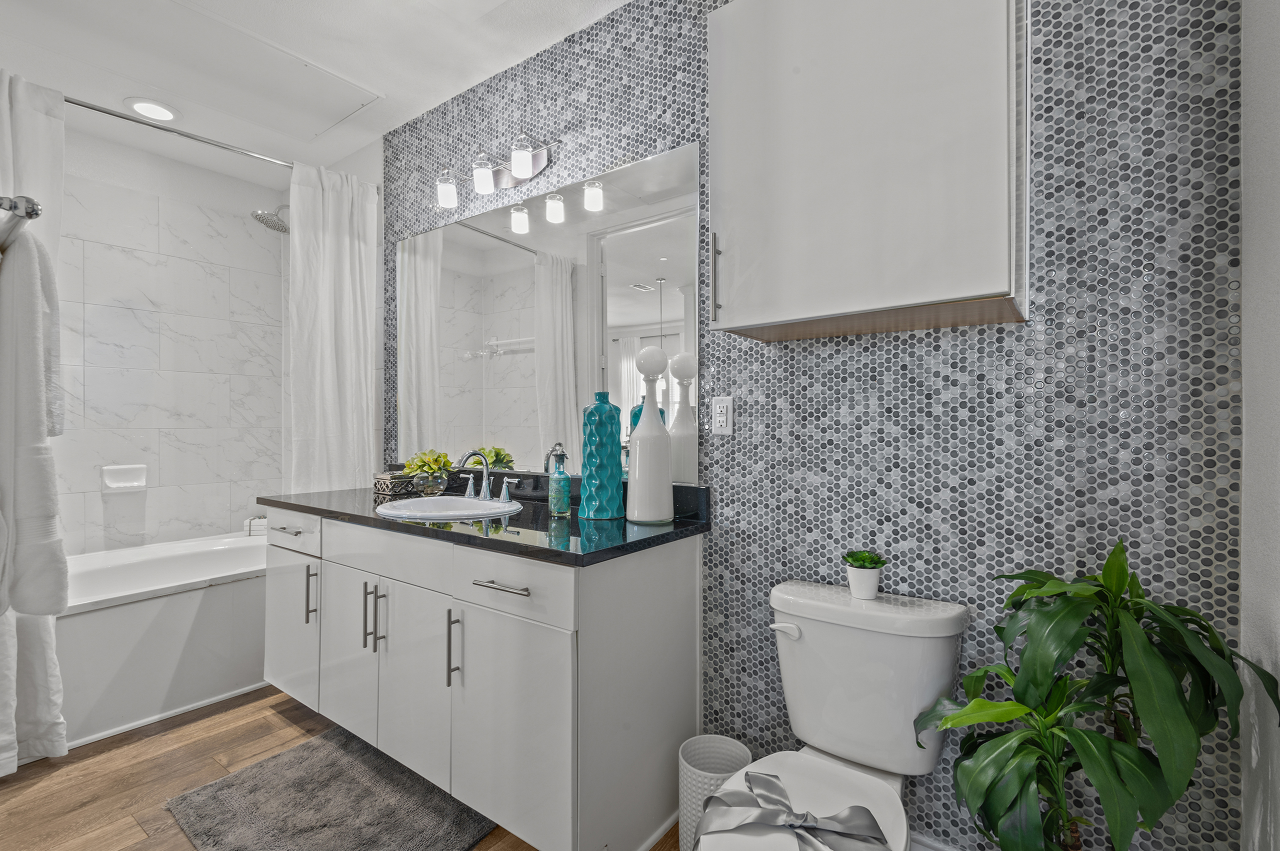 Contemporary bathroom with elegant gray mosaic tiles, sleek white cabinetry, and modern fixtures, creating a serene spa-like atmosphere.